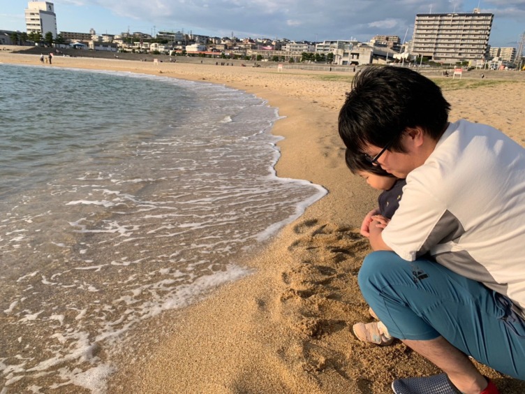 明石市役所の下村さんの休日の育児風景。大蔵海岸の浜辺を子どもと散歩する様子