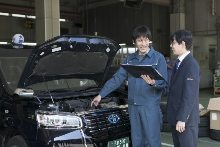 大和自動車交通株式会社のタクシーを点検しているスタッフとドライバーが立って話している様子