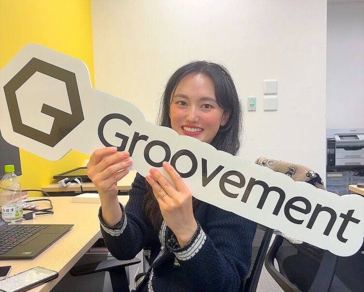 株式会社Groovementのロゴを手にする女性社員