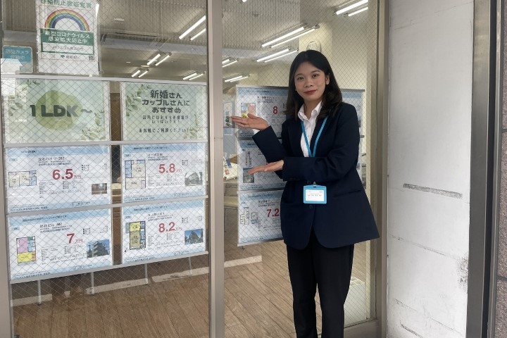 ハウスコム株式会社の女性社員が店舗の入り口で客を出迎えている様子