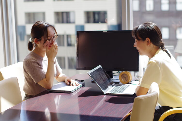 談笑しながら打ち合わせをするピースマインド株式会社の二人の女性社員