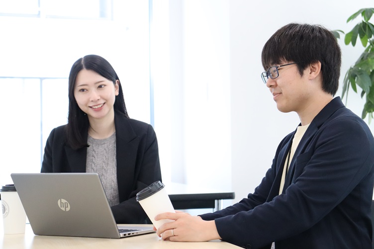 六元素情報システム株式会社の管理本部で人事採用担当をしている奥村龍太郎さんと古川みくさんがPCに向かって談笑している様子 その2
