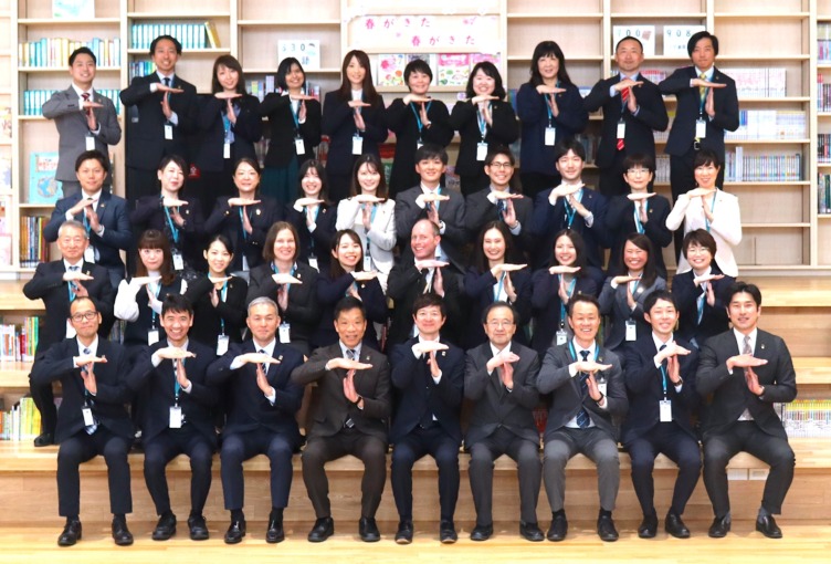 田中学園立命館慶祥小学校の教員が集合写真で同じポーズをしている様子